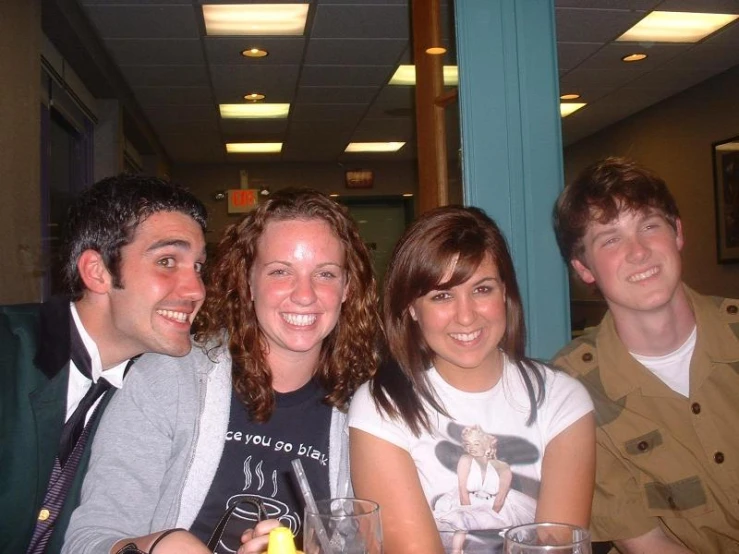 four people sitting together and smiling at a dinner