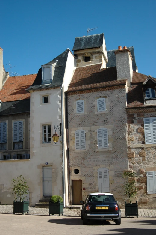 a car is parked near the front of some old houses