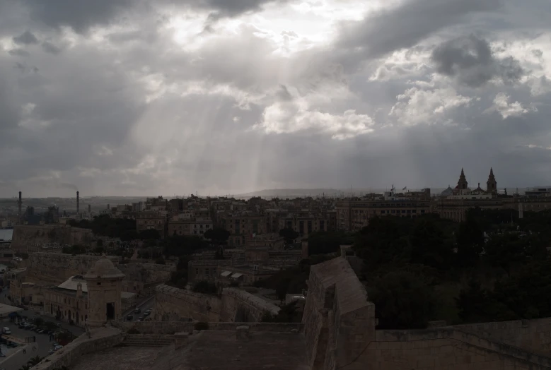 the sun shines through clouds above some buildings