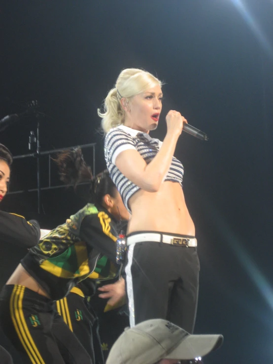 woman in striped top and pants singing on stage