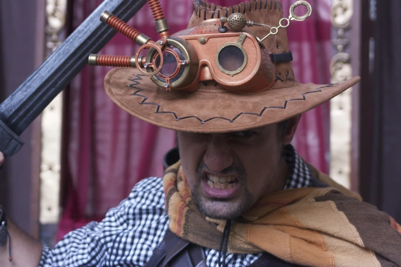 a man with a hat, goggles and gloves holds a pair of knives