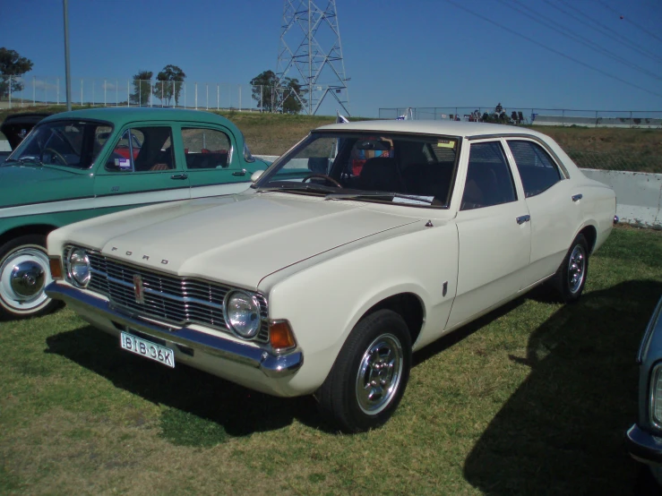 a white car parked next to other cars on grass