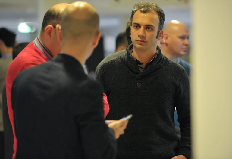 men talk to each other in a crowded room