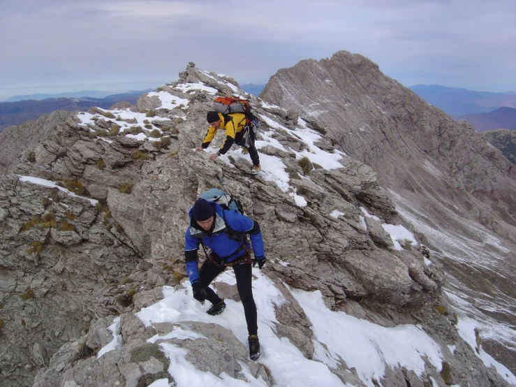 two men walking up a snowy mountain on top of a mountain