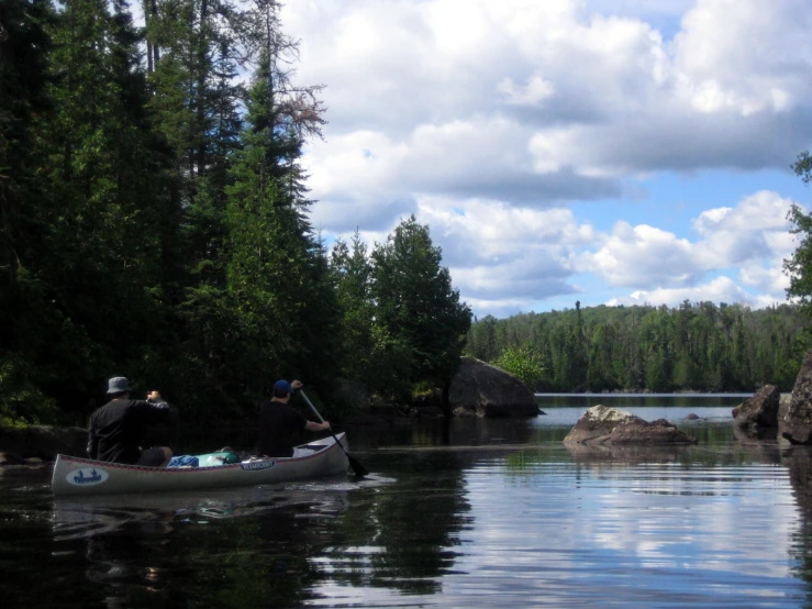 two people paddling a canoe down a river surrounded by rocks