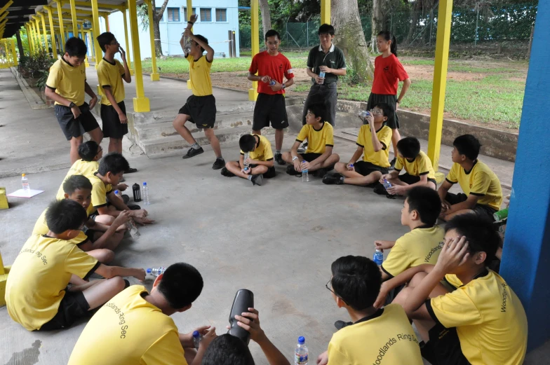 there are people in yellow shirts sitting and looking at their phones