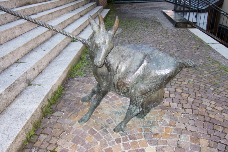 a metal statue of a goat tied to a chain