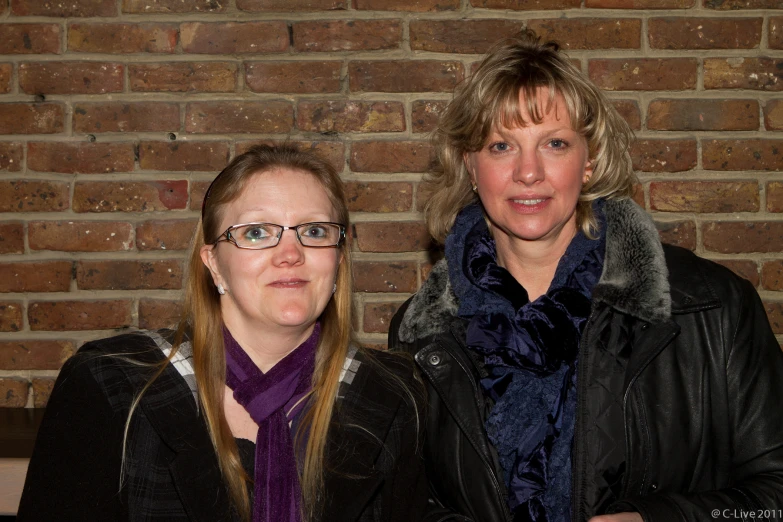 a close up of two women near a brick wall