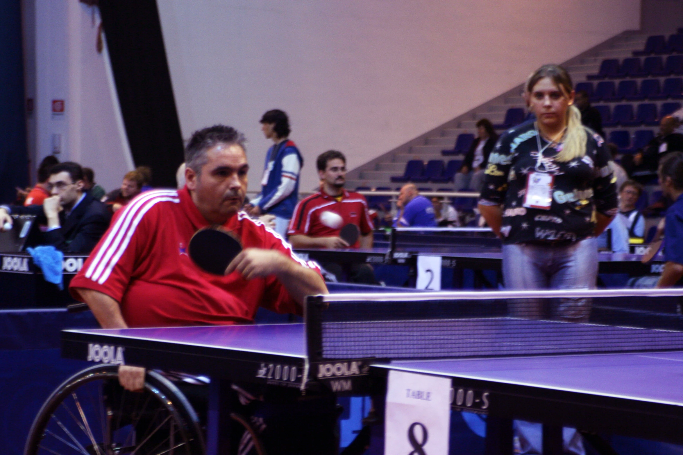 a table tennis player is sitting down while others watch