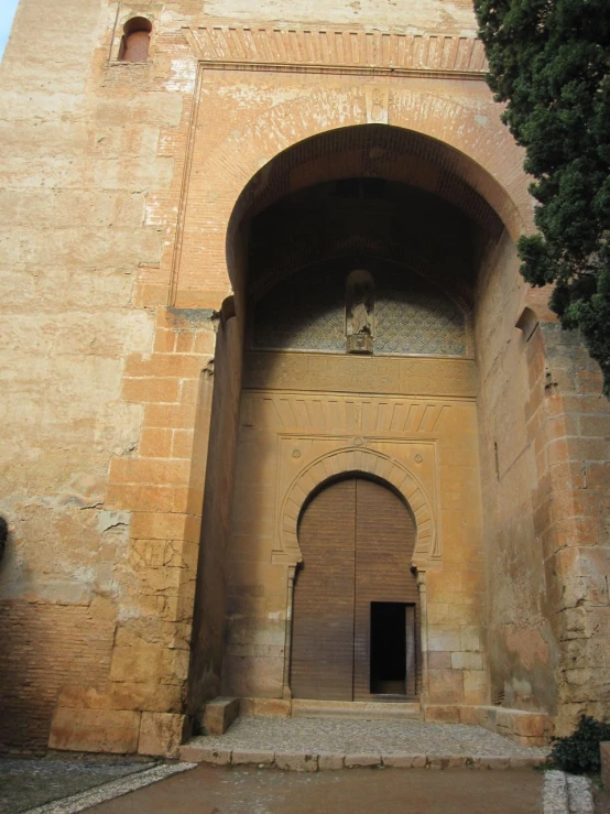 the building has two large doors and is surrounded by a small tree