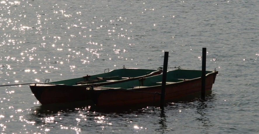 a boat is tied to poles on a still calm lake