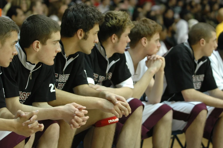 there are many young men sitting together watching a game