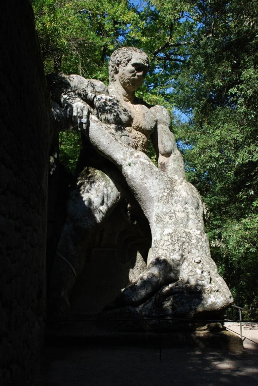 a stone statue of a boy is next to a forest