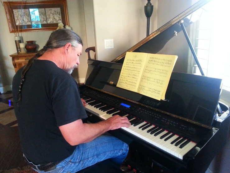 an older man sitting at a grand piano