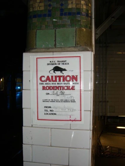 a sign on the side of a building warns against the rat