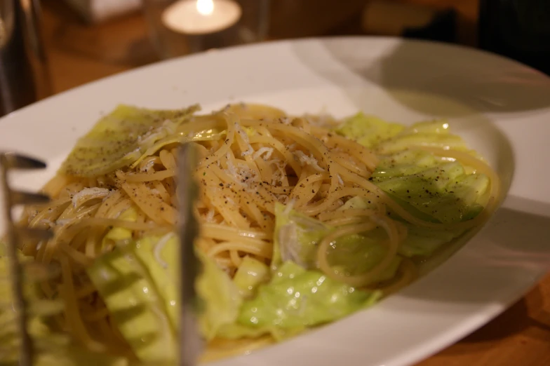 a plate of noodles with avocado and sauce with two fork in it