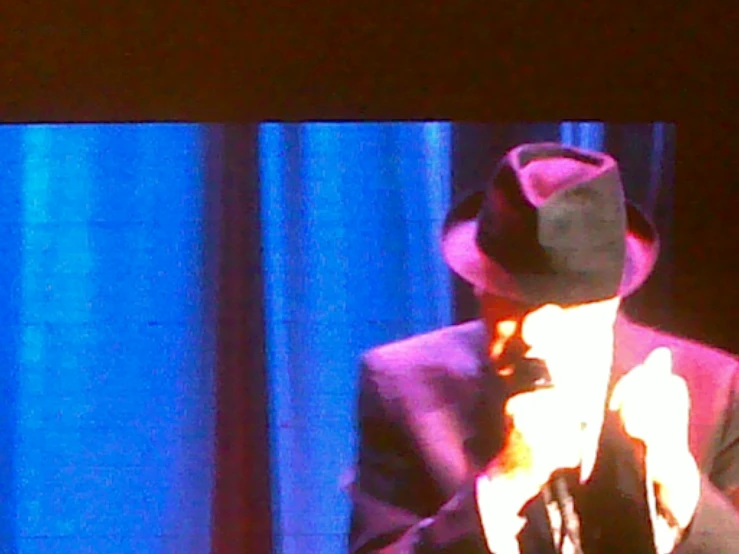 a male in a hat and suit with a microphone