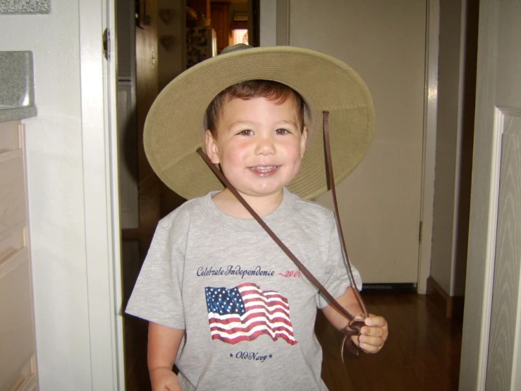 a young child wearing a hat holding two canes