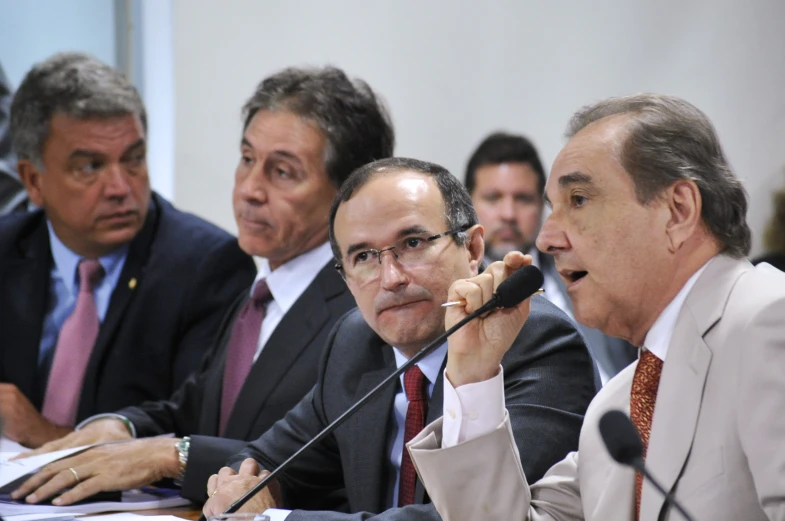 a bunch of men are sitting in front of microphones