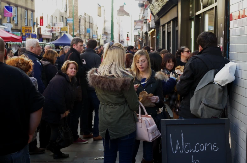 people walking through a crowded city street near stores