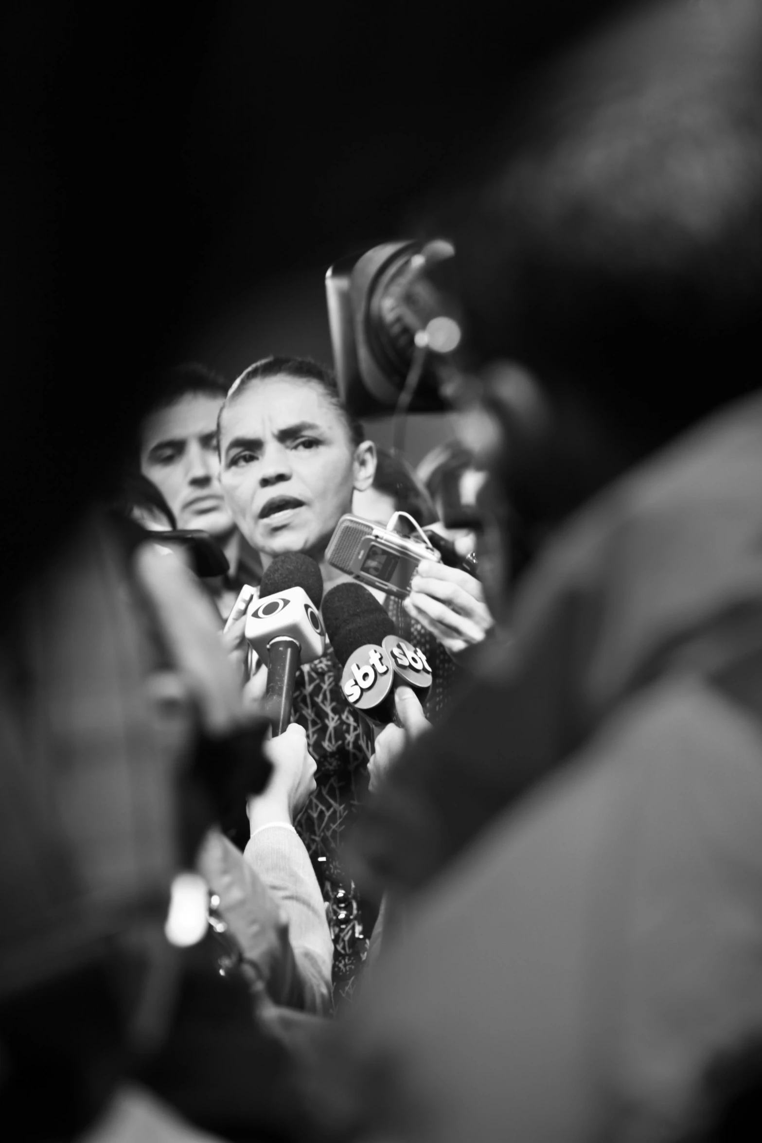 woman surrounded by press reporters in a crowd