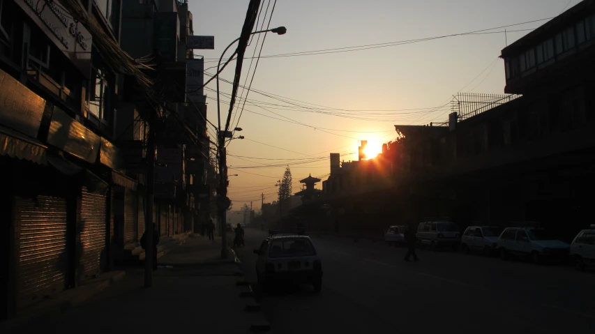 the sun sets in the background on an otherwise empty street