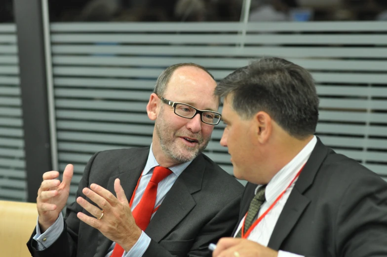 two men with ties sitting at a table having conversation