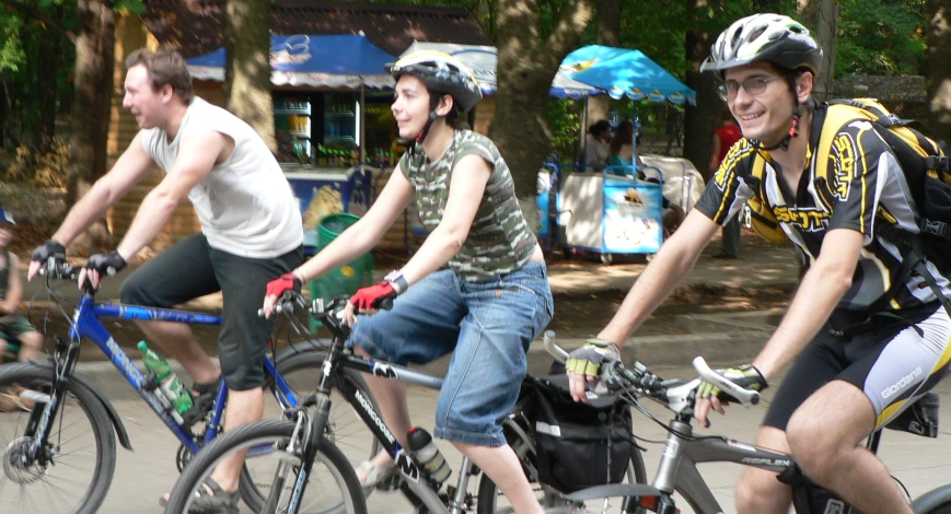 group of men riding bicycles next to a bunch of trees