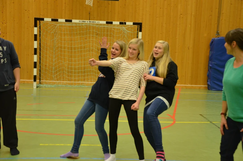 three girls standing in a gym playing frisbee