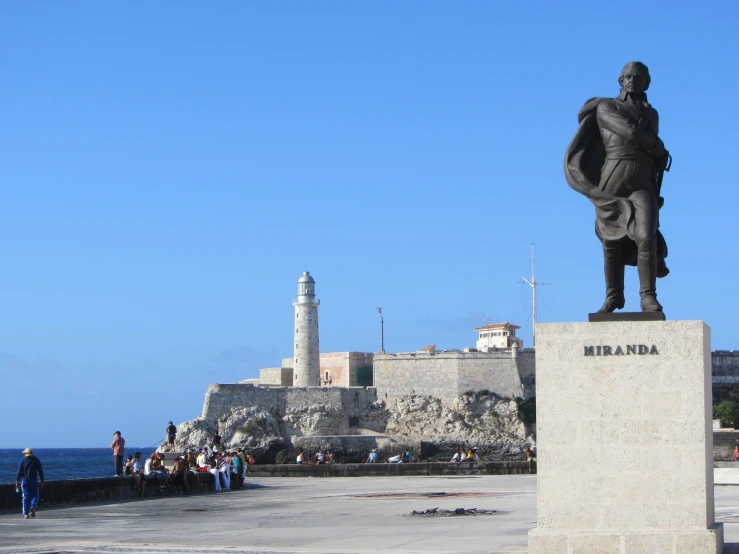 a statue on a small stone wall near a lighthouse