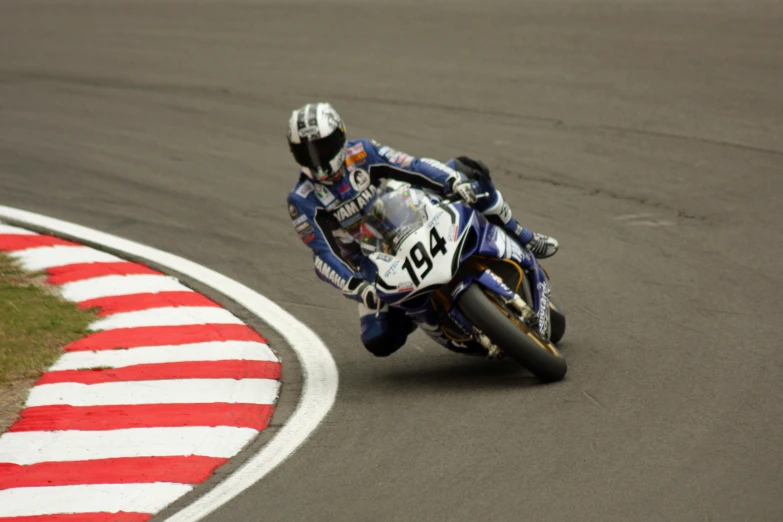 person with helmet and motorcycle racing on track