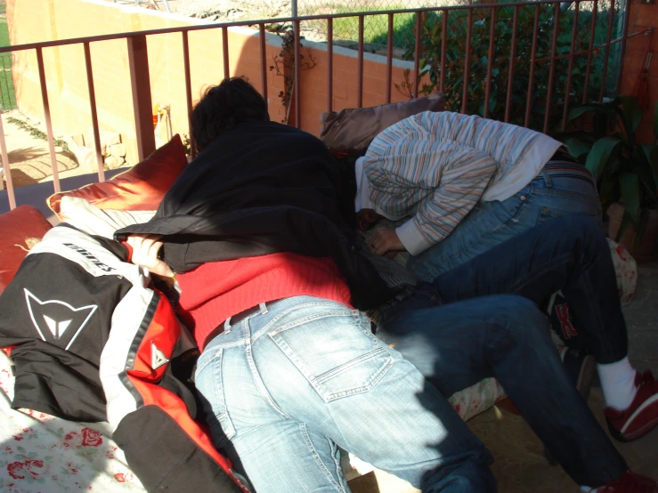 two men are asleep on a couch outside