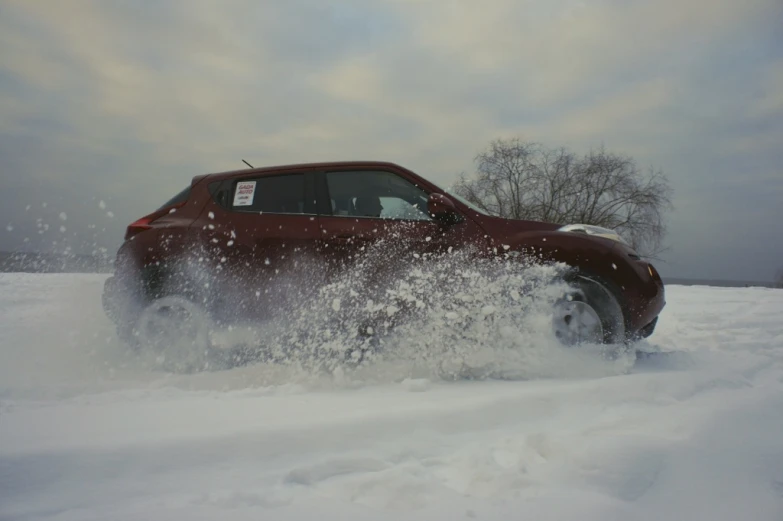 a red suv is driving through some snow