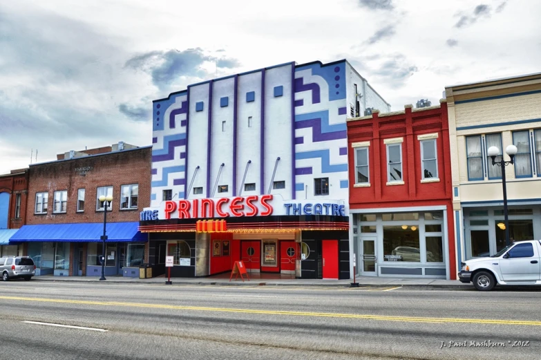 several buildings on a street with one theatre building in the background