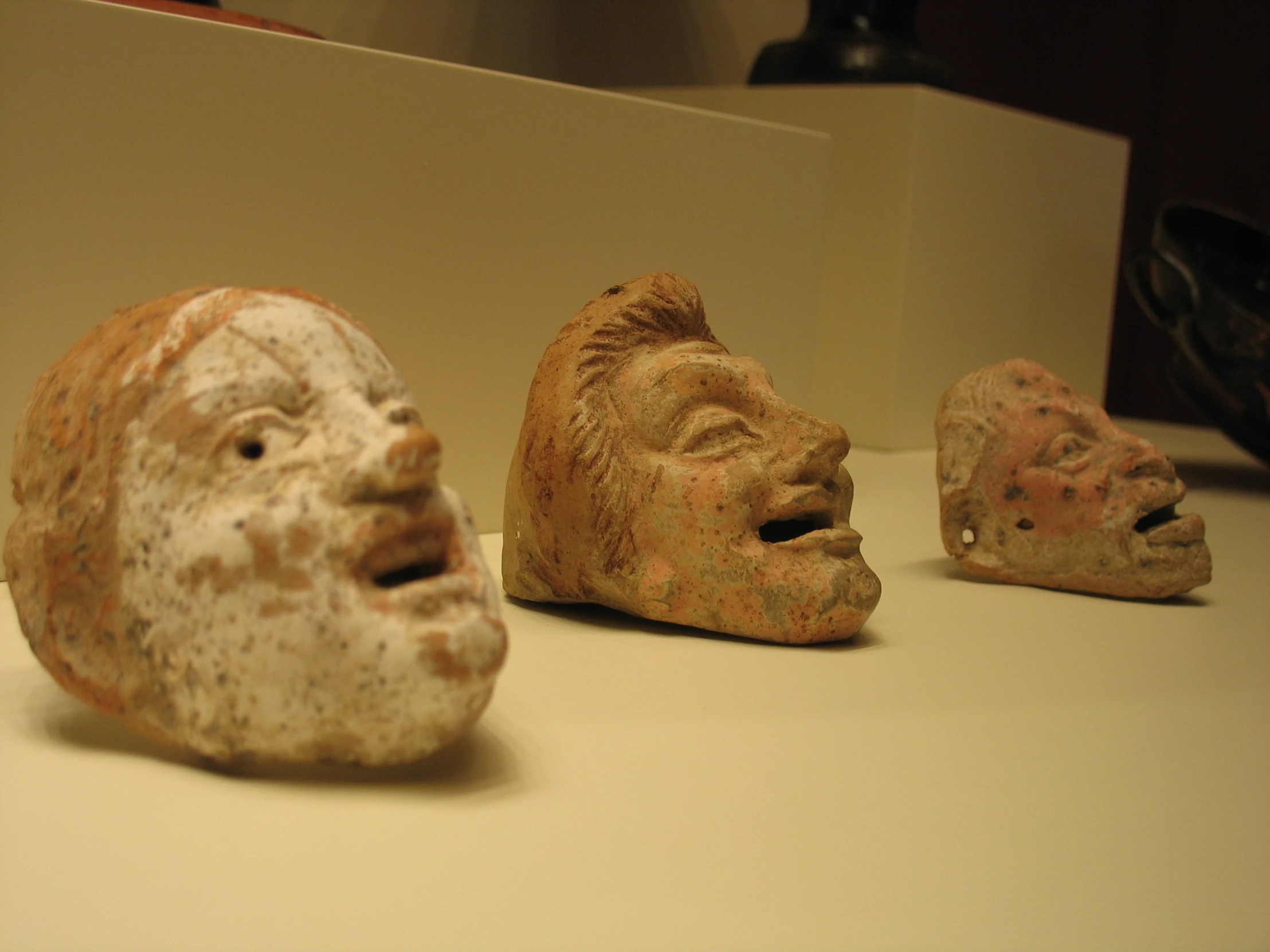 three masks and an object of art on display