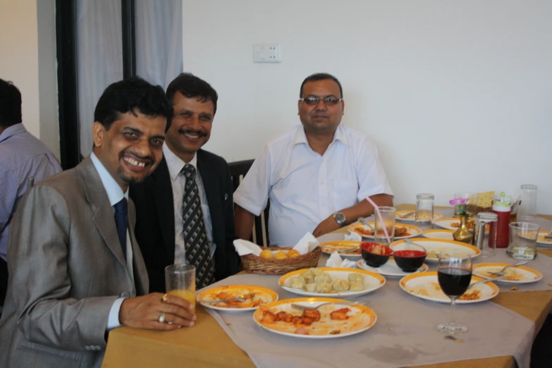 three men enjoying dinner at a restaurant table