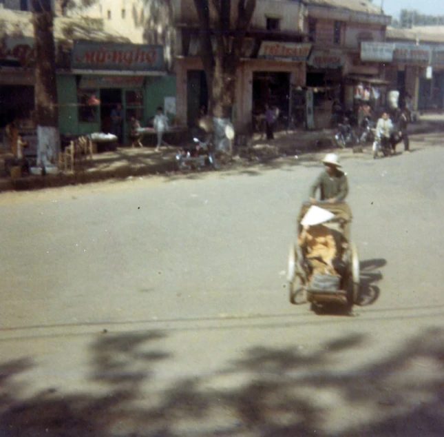 an old po shows people walking on the sidewalk as a motorcycle rides past them