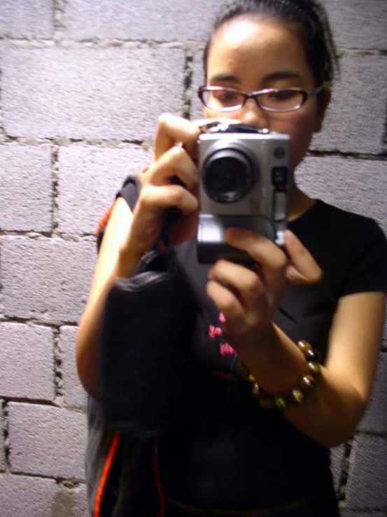 a girl taking a selfie in front of a brick wall