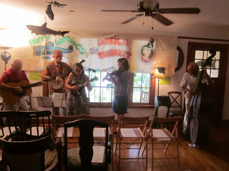 a group of people playing guitars and singing on wooden floors