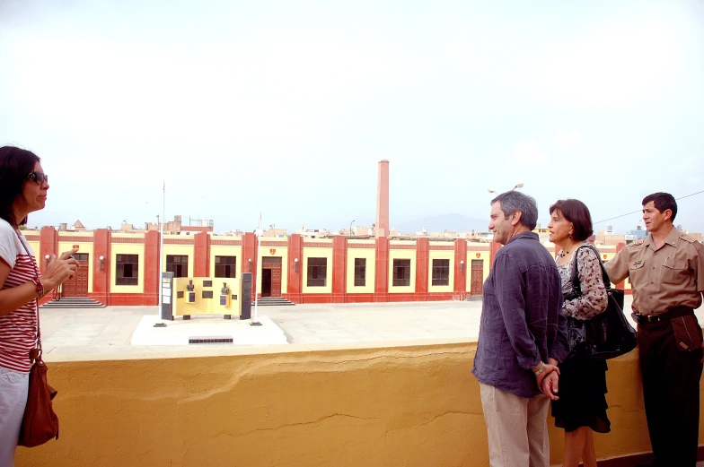 three people stand on a ledge, looking at the model city