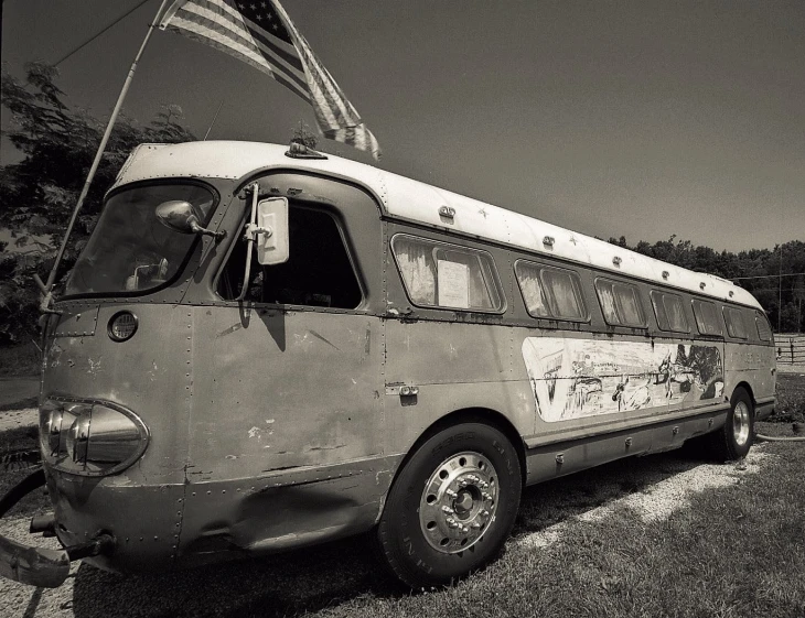 an old bus with a flag on top of it