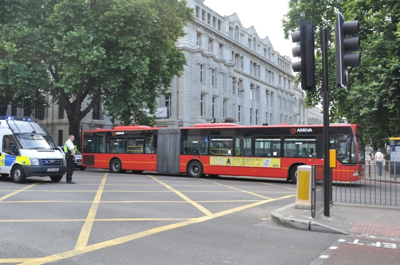 two buses on city street with cars and trees