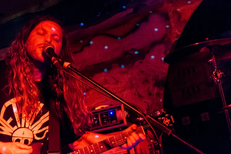 a guy with long hair playing a guitar