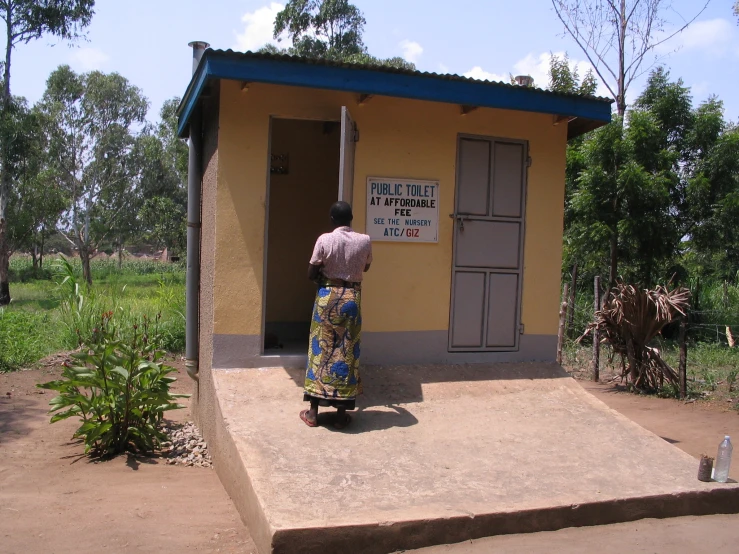 a man standing next to a small yellow building