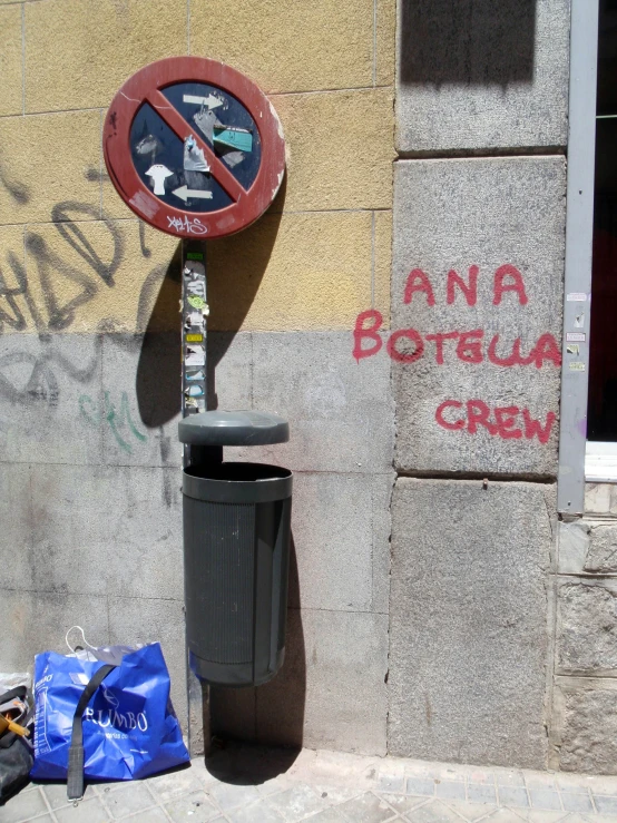 a trash can and street sign with graffiti