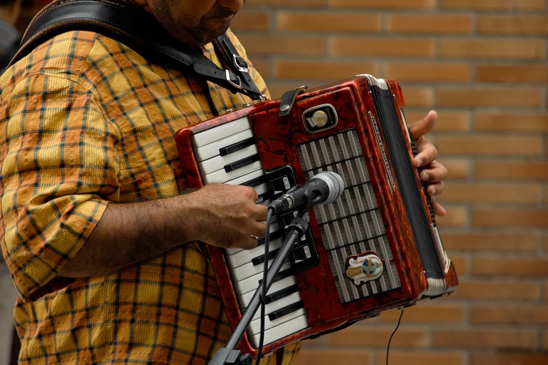 a man holding a red accordion near a microphone