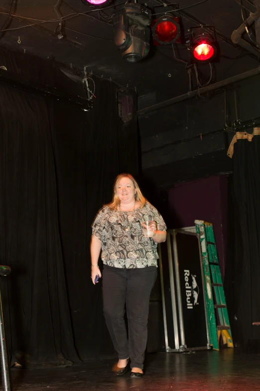 a woman standing on top of a stage near a crowd of people