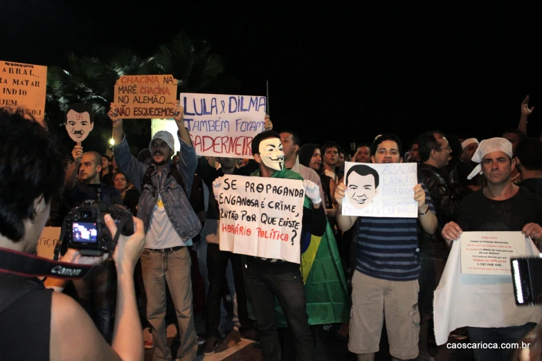 people holding signs and standing around with masks