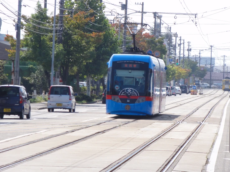 a trolley bus coming down the street in front of cars