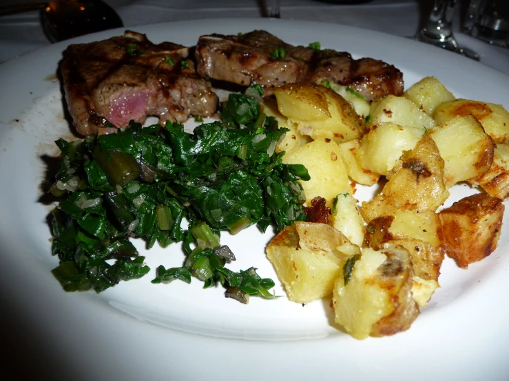 a plate full of food and potatoes, on a white table cloth